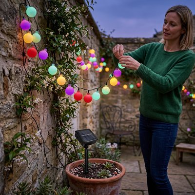 Guirlande lumineuse boule accrochee par femme sur muret