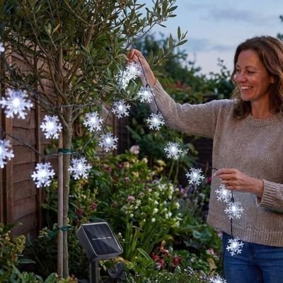guirlande lumineuse extérieur installee arbuste par femme
